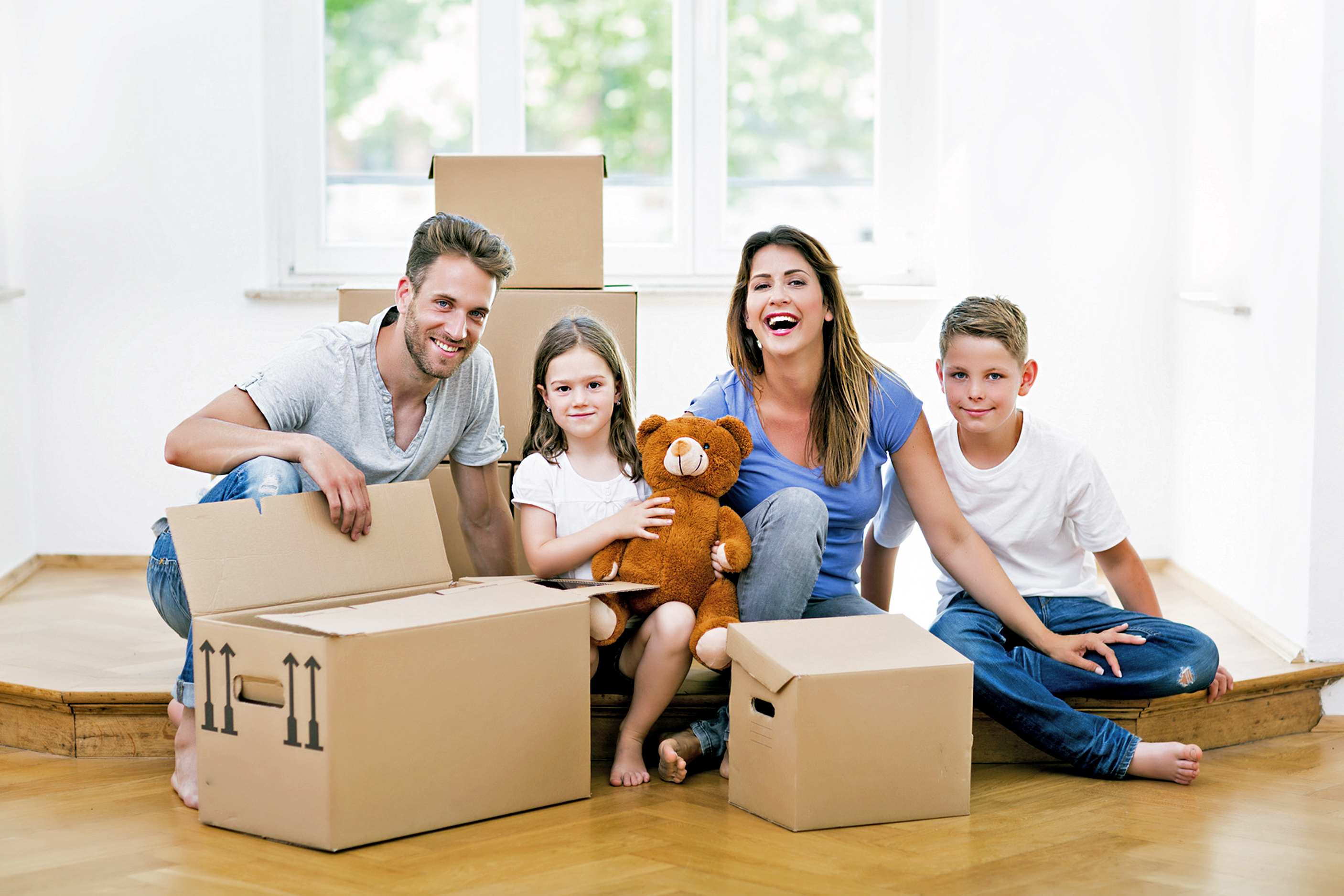 familie lacht und sitzt am boden, weil sie gerade von der hypo immobilien und leasing ein haus gekauft haben