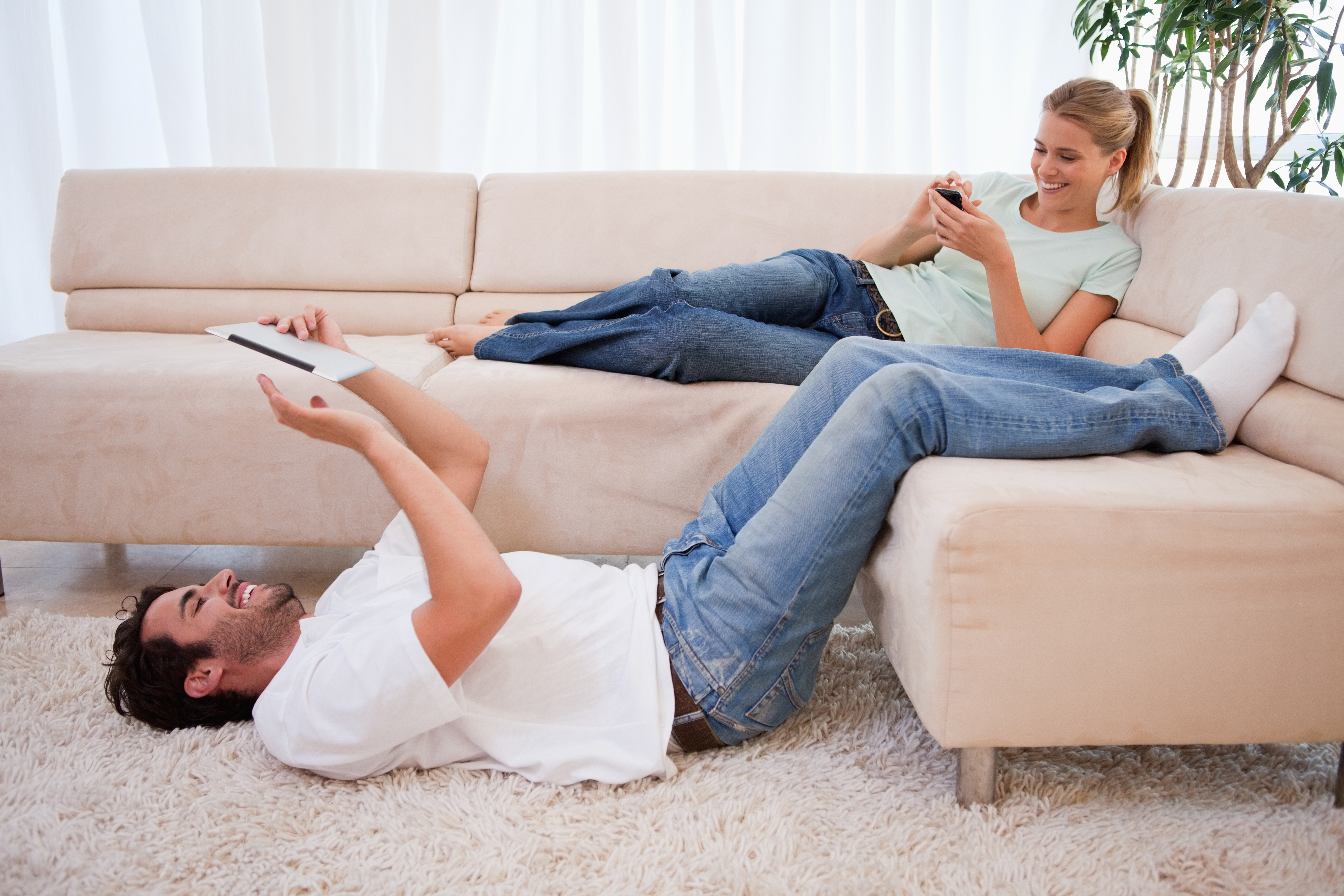 mann und frau liegen auf der couch und freuen sich über ihre neue immobilie