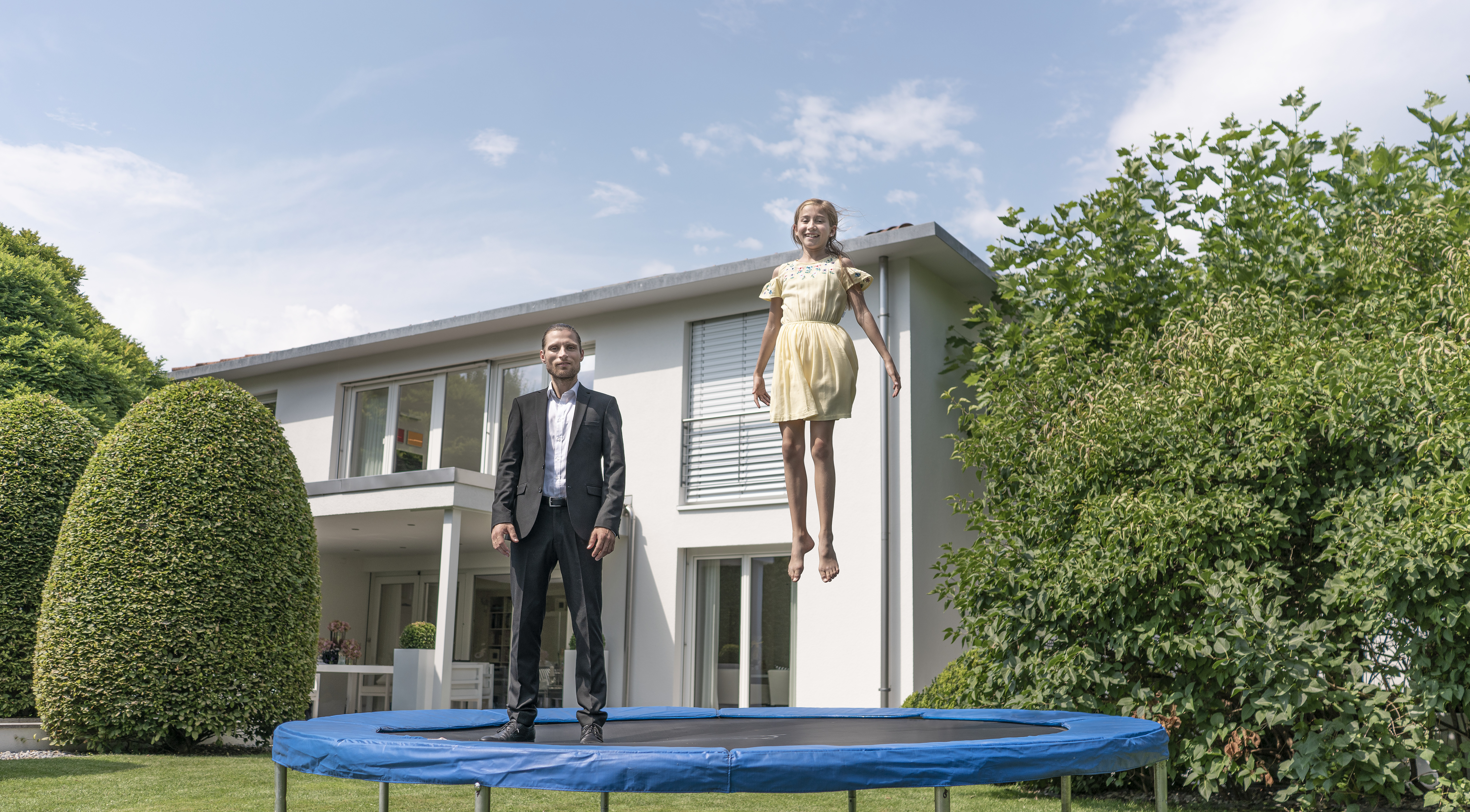 hypo immobilien und leasing berater steht mit mädchen auf trampolin