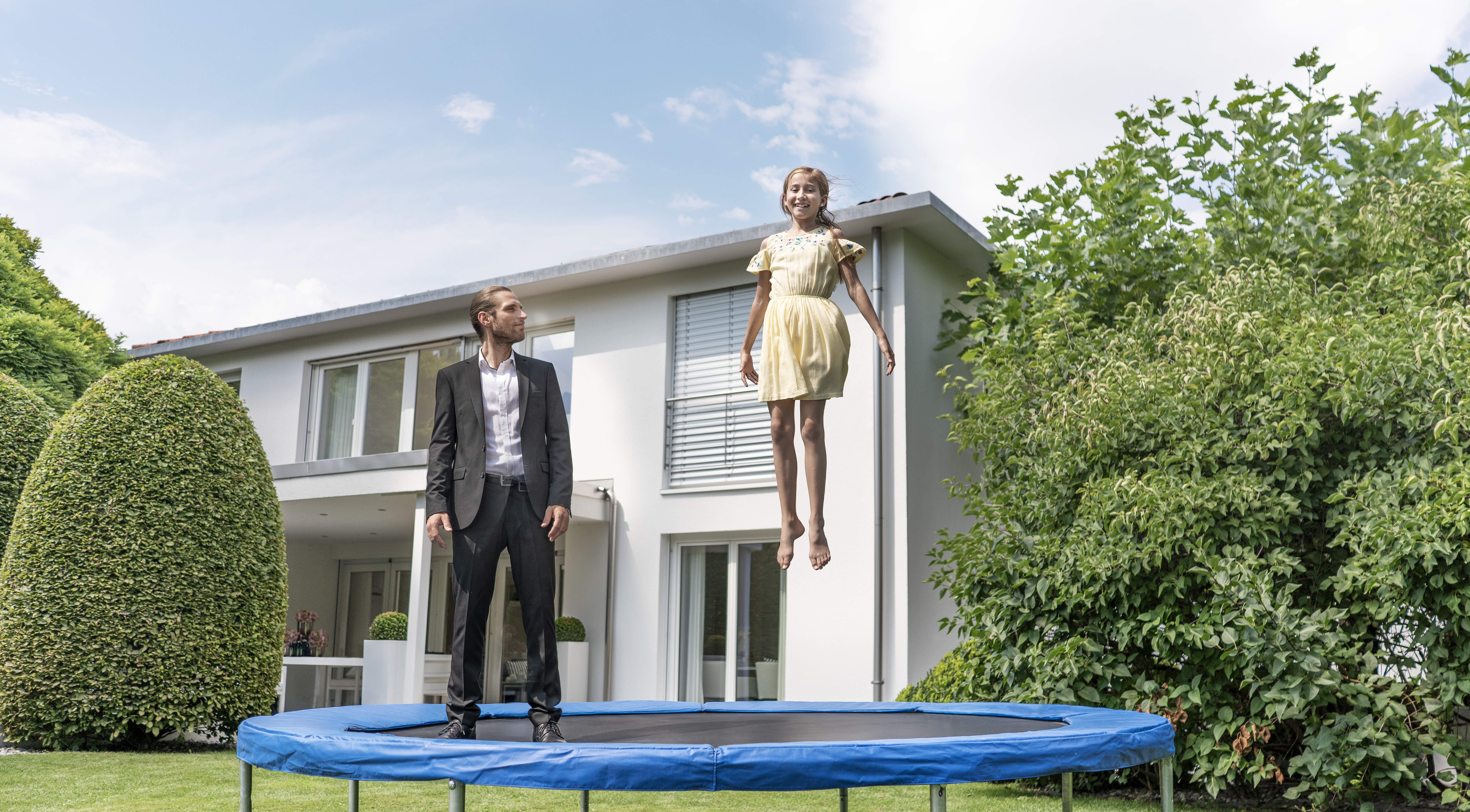 hypo immobilien und leasing makler hüpft mit kind vor einem weißen haus