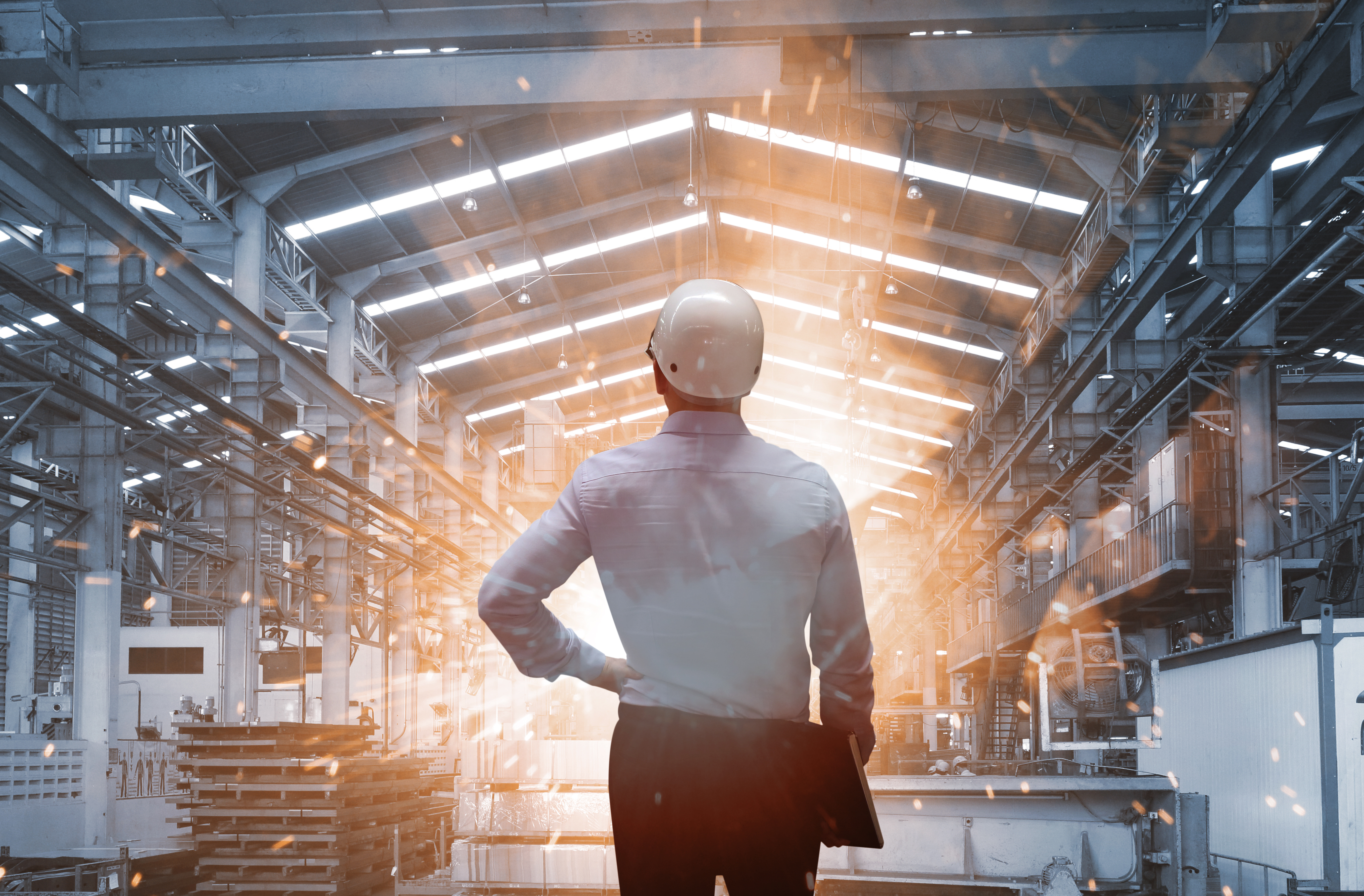 mann mit weißem helm steht in geleaster industrieanlage