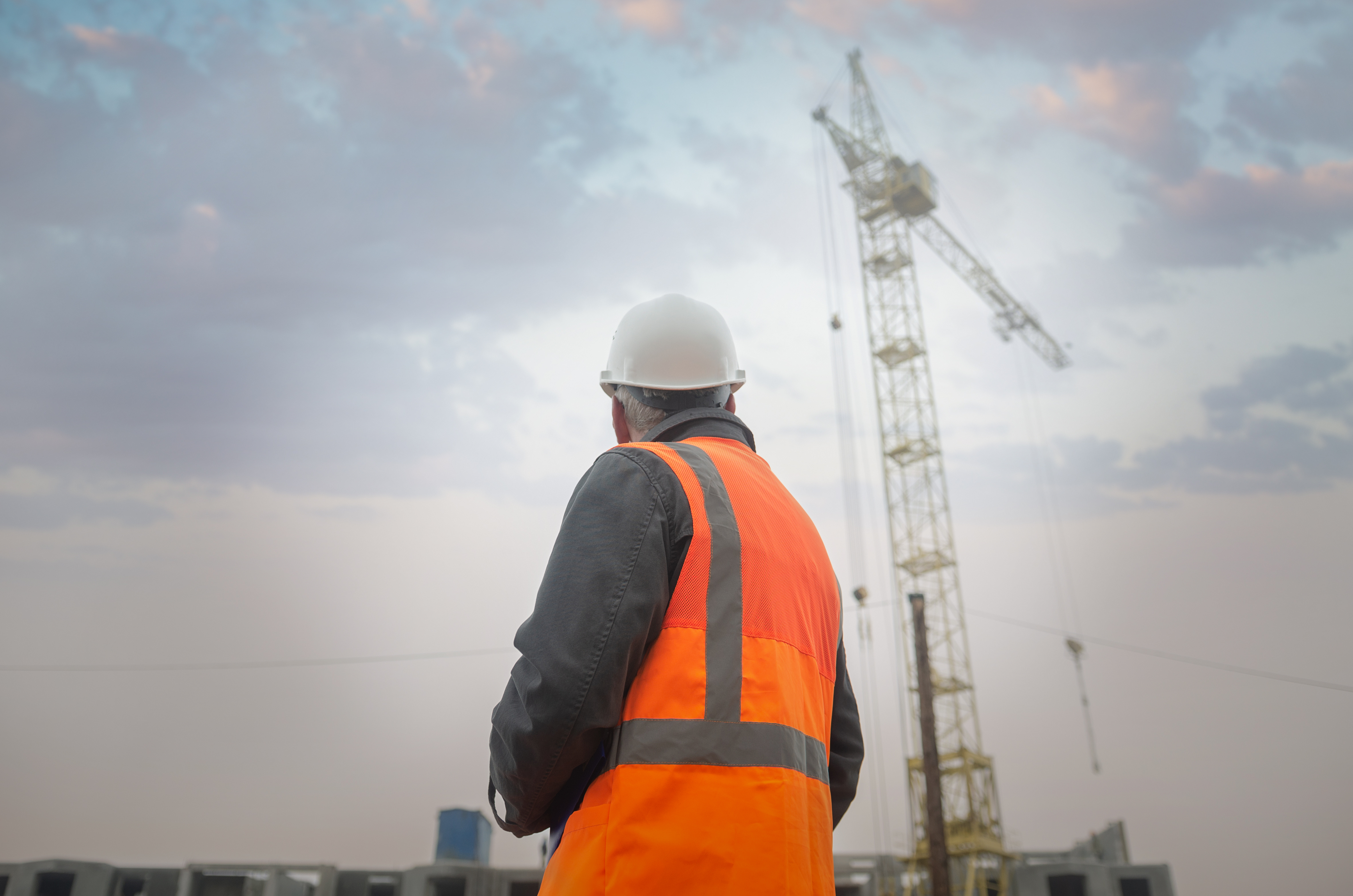 Rückenansicht eines Bauarbeiters vor einem Kran