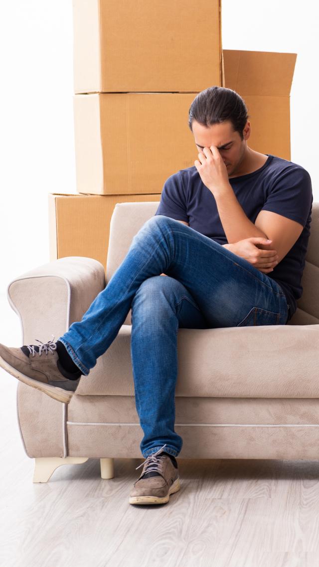 paar sitzt auf der couch mit kartons, immobilien news-artikel