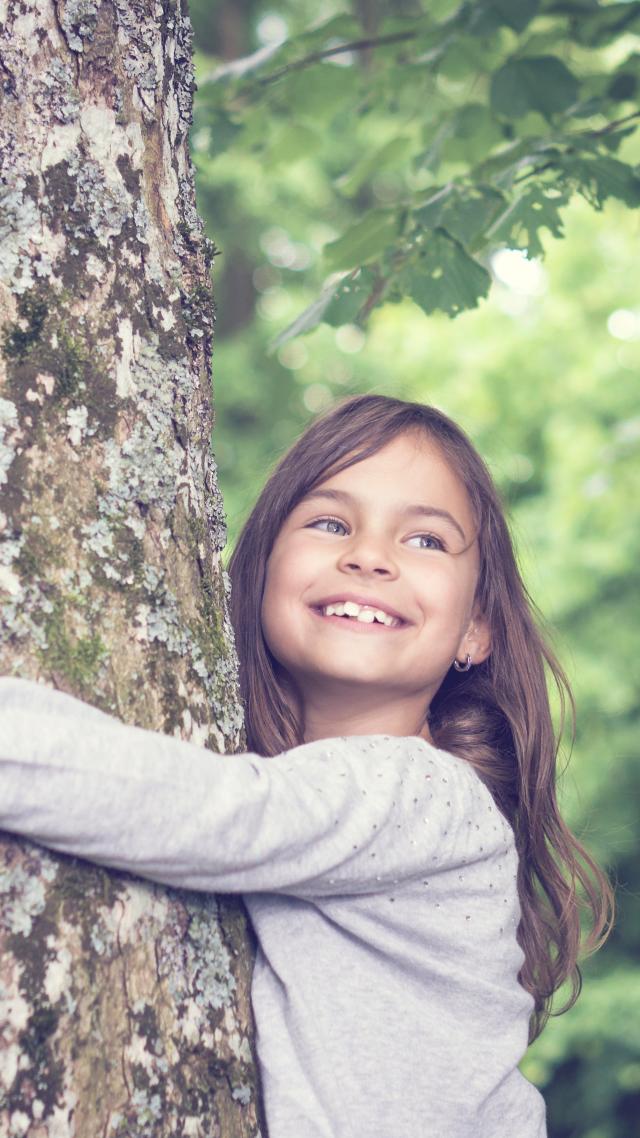 Kind umarmt den Baum. Foto für Leasing-News Artikel zum Thema Klimaneutral investieren. 