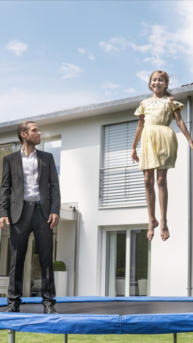 hypo immobilien und leasing makler hüpft mit kind vor einem weißen haus