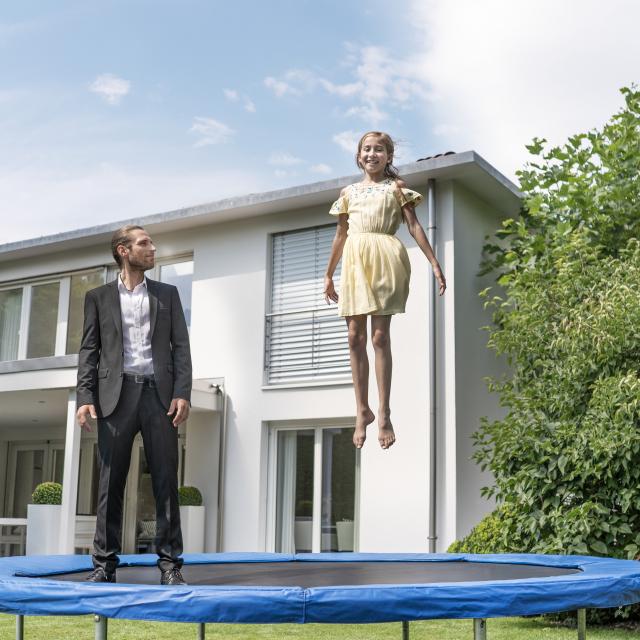 hypo immobilien und leasing makler hüpft mit kind vor einem weißen haus
