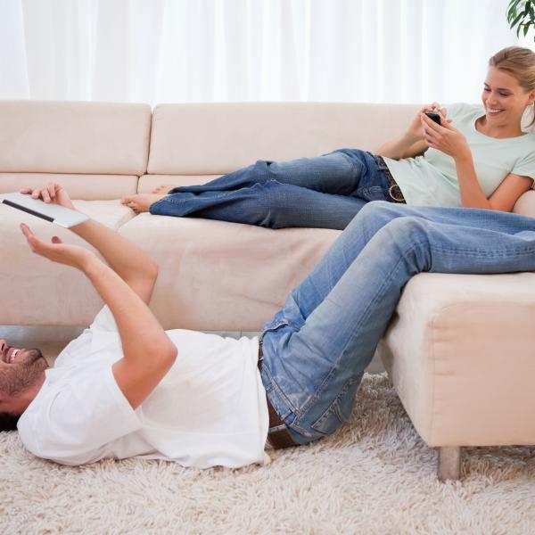mann und frau liegen auf der couch und freuen sich über ihre neue immobilie