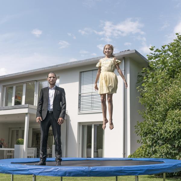 hypo immobilien und leasing berater steht mit mädchen auf trampolin 