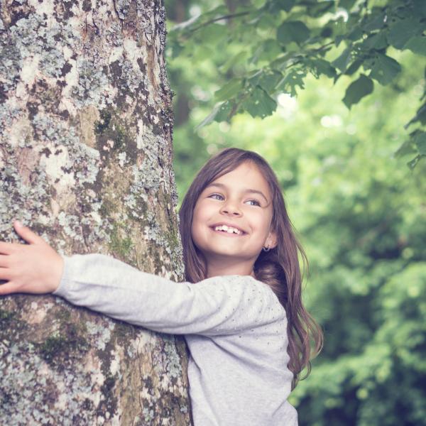 Kind umarmt den Baum. Foto für Leasing-News Artikel zum Thema Klimaneutral investieren. 