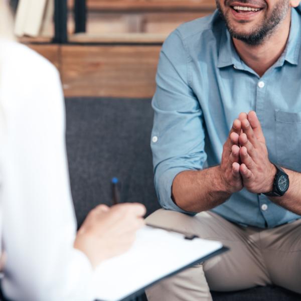 Ein Mann lacht und sitzt mit einer Maklerin der Hypo Immobilien auf der Couch