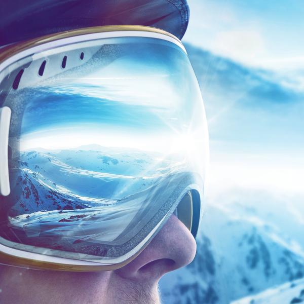 Frau mit Skibrille sieht auf Skigebiet